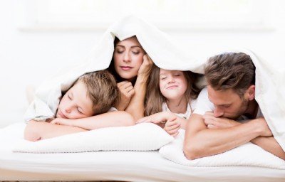 Familie liegt in einem Bett beim Matratzen testen